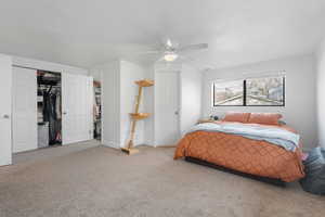 Bedroom featuring carpet flooring, a ceiling fan, and a walk in closet