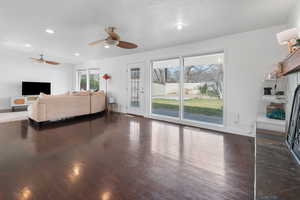 Living area featuring dark wood-style flooring, ceiling fan, and recessed lighting