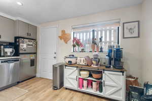 Kitchen with stainless steel appliances, light wood finished floors, gray cabinets, and wooden counters