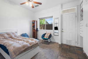 Bedroom with dark colored carpet, stone tile flooring, ceiling fan, and ornamental molding