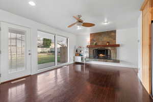 Unfurnished living room with a fireplace, dark wood finished floors, and ceiling fan