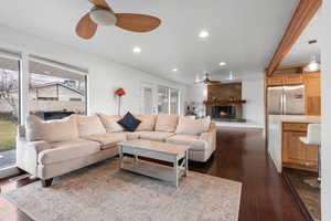 Living room with a fireplace, ceiling fan, recessed lighting, and dark wood-style floors