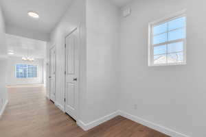 Corridor featuring light wood-type flooring and a chandelier