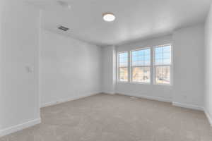 Spare room with a textured ceiling and light colored carpet