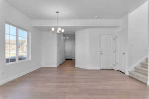 Unfurnished dining area featuring hanging lights and light wood-style floors