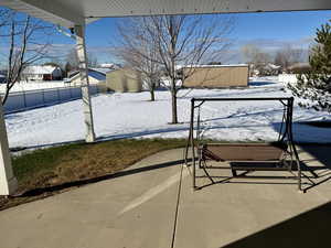 Snowy yard with a fenced backyard