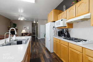 Kitchen with light countertops, light brown cabinetry, white appliances, under cabinet range hood, and dark wood-style flooring