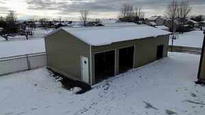 Snow covered garage featuring a detached garage