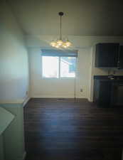 Unfurnished dining area with dark wood finished floors and a chandelier
