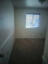 Unfurnished room with dark colored carpet and a textured ceiling