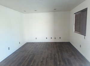 Empty room featuring dark wood-style floors and baseboards