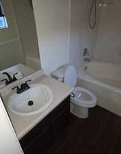 Bathroom featuring vanity, shower / bath combination, and dark wood-style floors