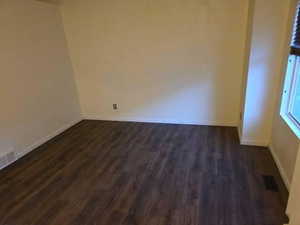 Empty room featuring dark wood finished floors and baseboards