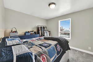 Carpeted bedroom with a textured ceiling and a wainscoted wall