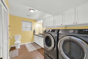 Laundry room featuring light tile patterned floors and washing machine and clothes dryer