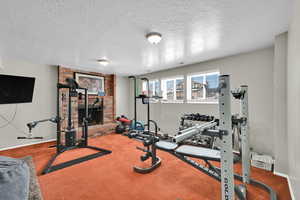 Workout room featuring a textured ceiling, carpet, and a fireplace