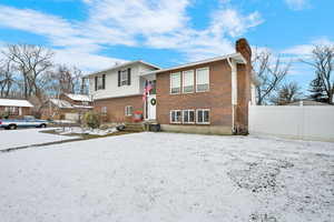 View of front of house featuring a chimney and brick siding