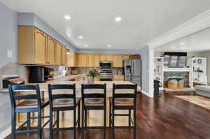 Kitchen featuring light countertops, light brown cabinets, appliances with stainless steel finishes, recessed lighting, and a stone fireplace