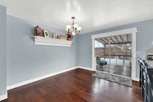 Unfurnished dining area featuring a textured ceiling, dark wood-style floors, and a chandelier