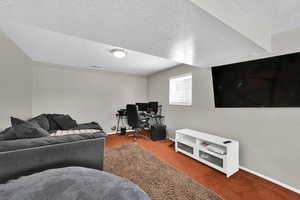 Living room featuring a textured ceiling, a desk, and carpet floors