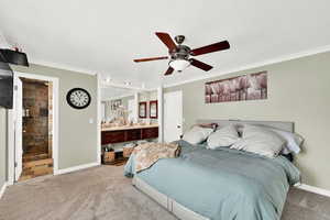 Bedroom with light carpet, ensuite bathroom, ceiling fan, and ornamental molding