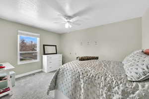 Bedroom with carpet floors, ceiling fan, and a textured ceiling