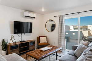 Living room featuring a wall mounted AC, wood finished floors, and recessed lighting