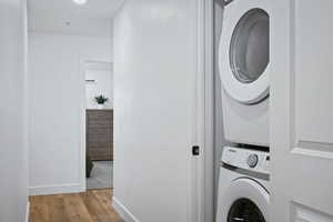 Washroom with light wood-type flooring and estacked washer and dryer
