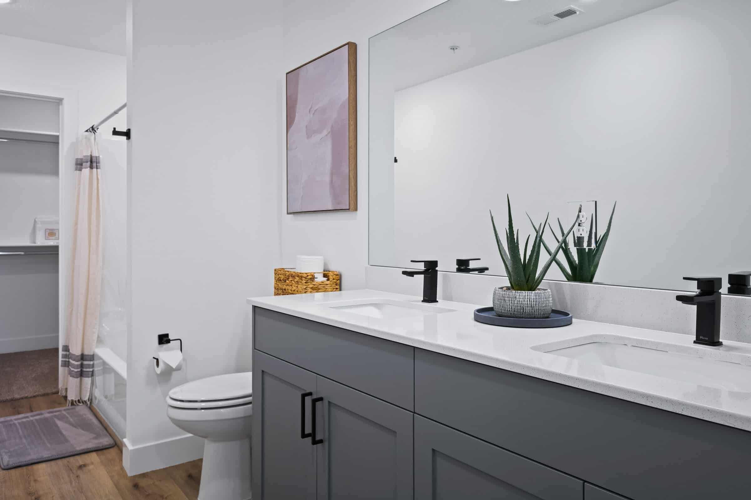 Full bathroom with double vanity, a shower stall, and light wood-style floors