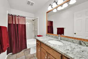 Bathroom with vanity, shower / tub combo with curtain, and light tile patterned flooring