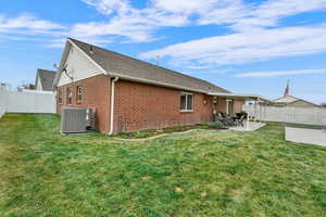 Rear view of house featuring a fenced backyard, a patio, brick siding, and roof with shingles