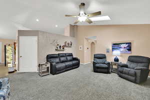 Living area featuring lofted ceiling, arched walkways, carpet flooring, recessed lighting, and ceiling fan