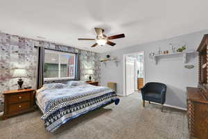 Bedroom with wallpapered walls, carpet, ceiling fan, and ensuite bath