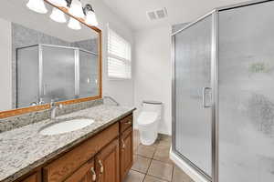 Bathroom with a stall shower, light tile patterned floors, and vanity