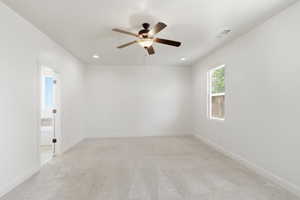 Spacious room featuring light-toned carpeting, a ceiling fan with integrated lighting, recessed lighting fixtures, and a single window for natural illumination