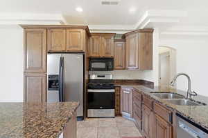 Kitchen featuring warm wood cabinetry, stainless steel appliances, granite countertops, and tile flooring