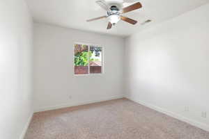 Light-filled room featuring a ceiling fan with light fixture, neutral carpet flooring, white baseboards, and a window offering natural light