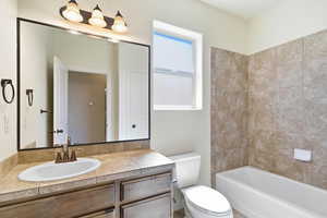 Bathroom featuring a vanity with an oval sink, tile countertop, and wood-finish cabinetry