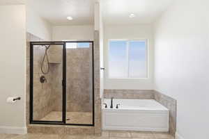 Full bathroom featuring a tiled walk-in shower with a black-framed glass enclosure, an integrated shower niche, and a separate soaking tub with a tiled surround