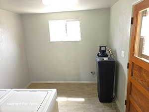 Laundry area with light wood-style flooring, washer / clothes dryer, a textured wall, and a textured ceiling