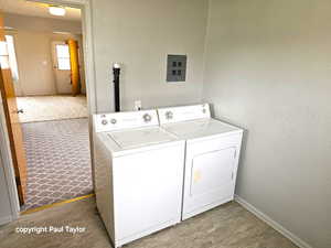 Laundry area featuring a textured wall, washing machine and dryer, and light wood-type flooring