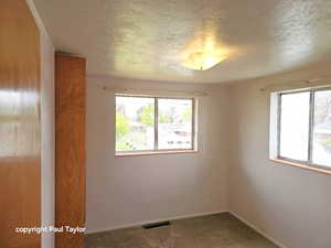 Unfurnished room with dark carpet and a textured ceiling