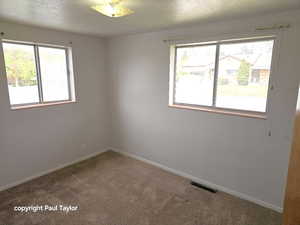 Carpeted spare room featuring baseboards and a textured ceiling