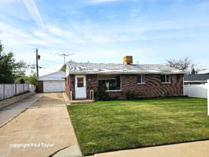 Ranch-style home featuring brick siding, a detached garage, and an outdoor structure
