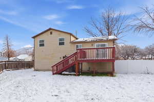 Snow covered property featuring a fenced backyard, stairs, a deck, and solar panels