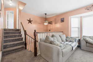 Carpeted living area with ceiling fan