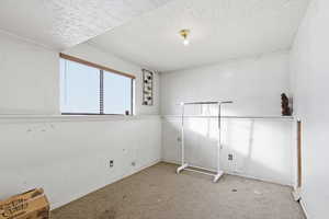 Unfurnished room featuring a textured ceiling and carpet