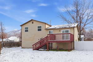 Snow covered property featuring a fenced backyard, stairs, and a deck