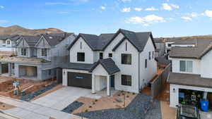 View of front of home featuring a residential view, a tiled roof, stucco siding, a garage, and driveway