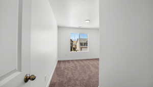 Empty room with carpet flooring and a textured ceiling